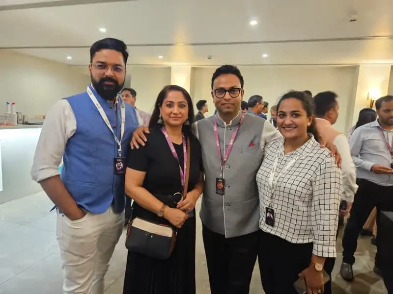 Four members wearing event lanyards standing together in a venue foyer