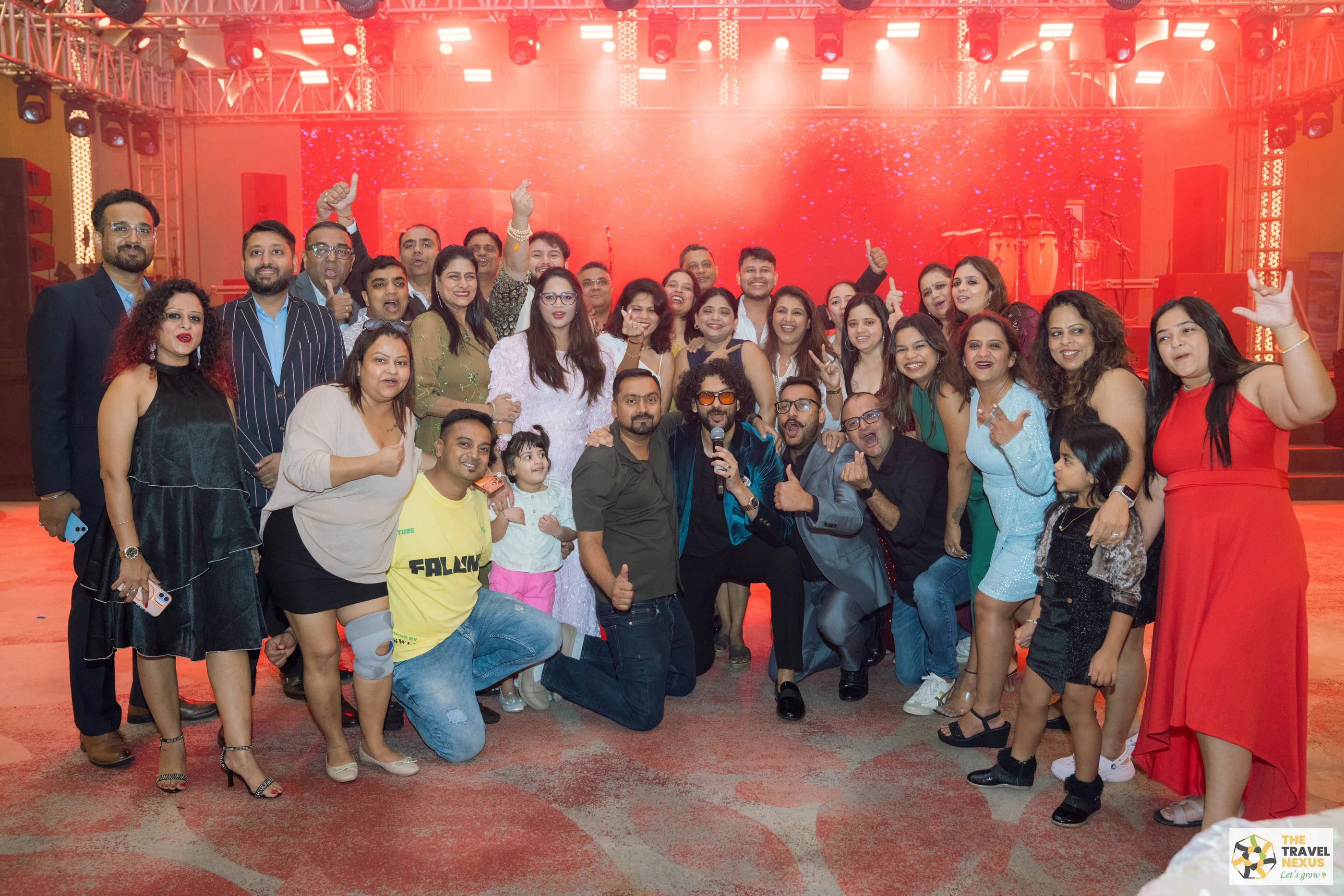 A large Travel Nexus group celebrating together in front of the stage