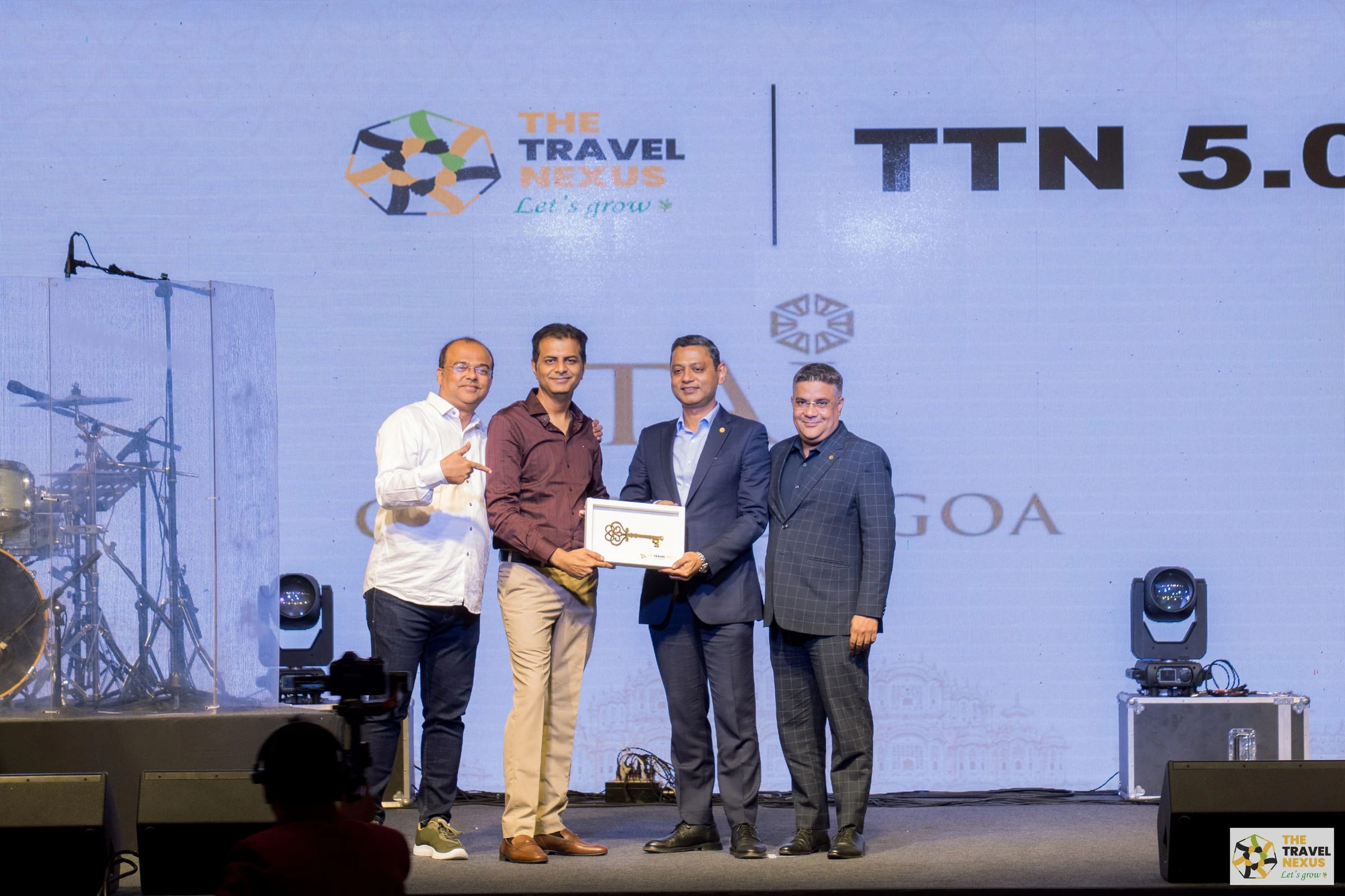 Four people presenting a framed recognition piece on the Travel Nexus stage