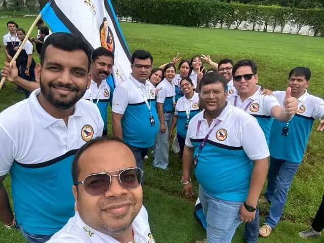 Travel Nexus members in matching shirts gathered outdoors with a group flag