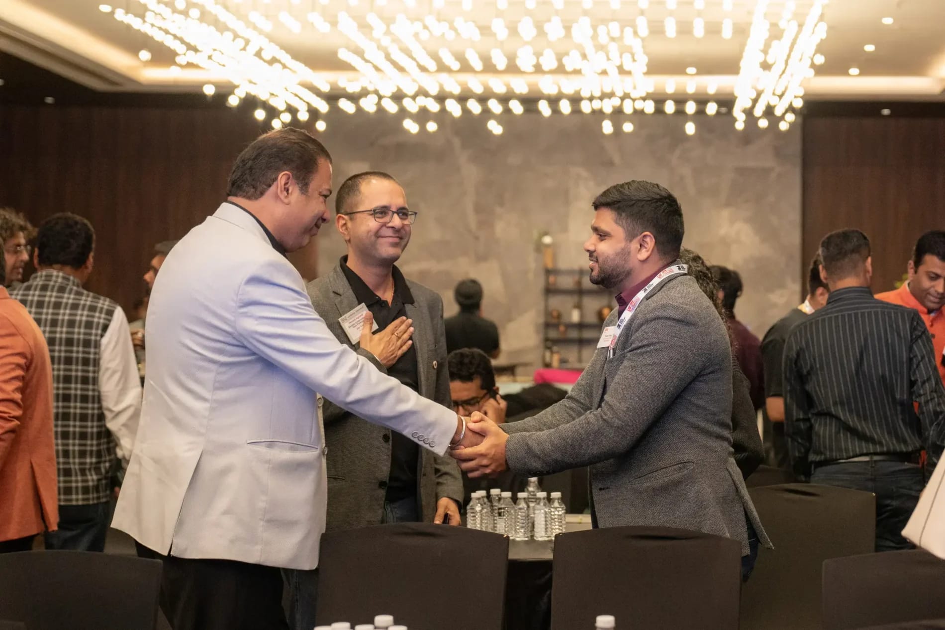 Two Travel Nexus members shaking hands at a members' meeting while a third looks on
