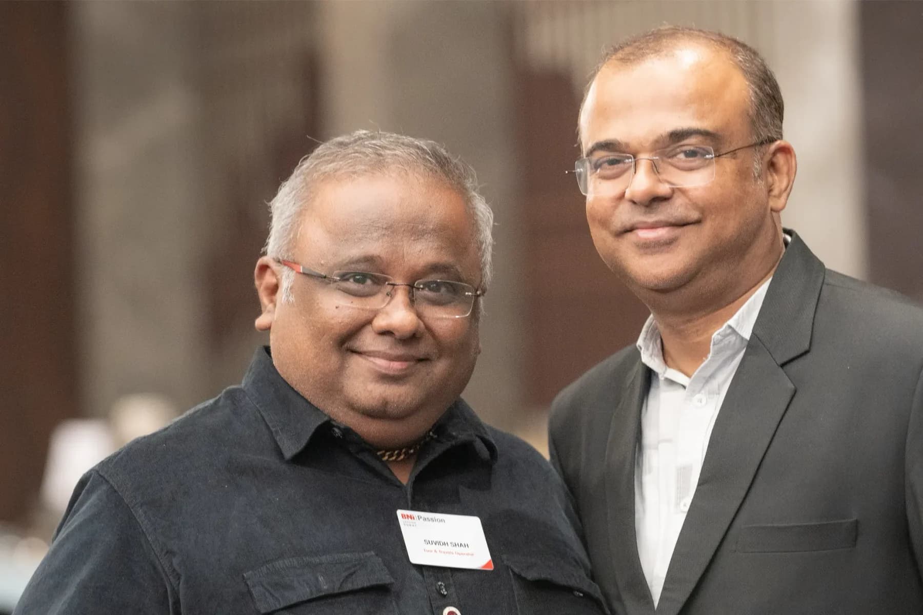 Two Travel Nexus members standing shoulder to shoulder, one wearing a BNI Passion name badge